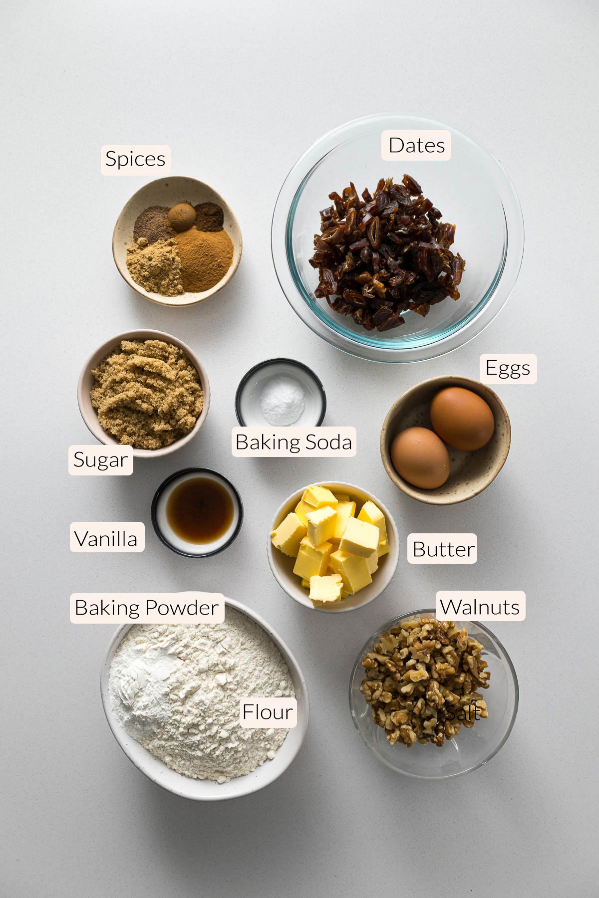 Date and walnut cake ingredients - spices, dates, sugar, baking soda, eggs, vanilla, butter, baking powder, flour, and walnuts.